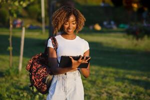 en ligne communication, éducation ou travail concept. jolie africain américain Dame avec tablette ordinateur à parc photo