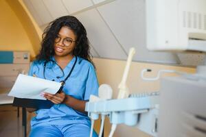 Jeune Afro-américain femelle médecin dans blanc manteau en utilisant ultra ultrason balayage machine et à la recherche sur le filtrer. africain femme médecin travail sur moderne ultrason équipement. photo