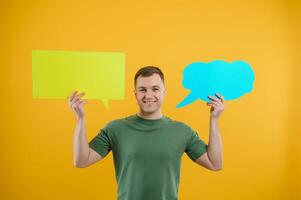 portrait de de bonne humeur souriant Jeune Beau homme en portant et à la recherche en haut à discours bulle avec vide espace pour texte sur coloré Jaune studio Contexte photo