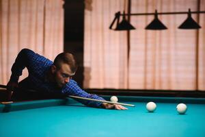 Jeu de billard le main de une homme avec une billard queue objectifs à une billard Balle photo