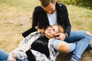 couple dans l'amour séance sur l'automne déchue feuilles dans une parc, profiter une magnifique l'automne journée photo