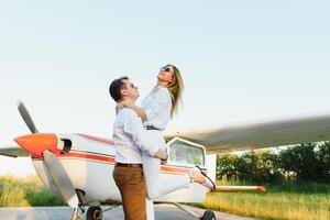 haute en volant romance. de face vue de souriant Jeune femme ferroutage sur sa copain tandis que en gardant bras tendu. privé avion Contexte photo