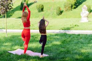 femme et enfant faire yoga dans le parc. été, soleil, mère et fille, santé. Extérieur des sports. en bonne santé sport mode de vie. aptitude, yoga photo