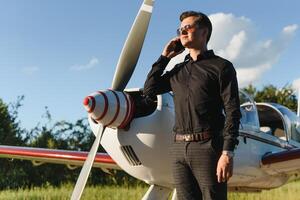 affaires homme avec le sien avions. il est en marchant dans le aéroport avec le intelligent téléphone et fabrication une appel. photo