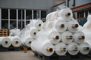 brut matériaux entrepôt. beaucoup grand bobines de fini propylène tuyau fabriqué de tissé fil pour fabrication industriel Sacs. polypropylène Rouleaux pour emballage. photo