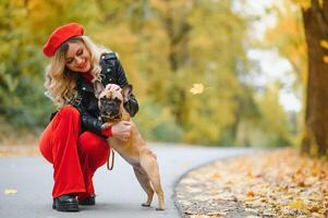 magnifique et content femme profiter dans parc en marchant avec sa adorable français bouledogue. photo