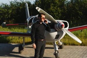 Beau homme d'affaire près privé jet. réussi homme à le aéroport parlant sur le téléphone. photo