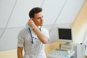 Masculin médecin dans masque avec ultrason équipement dans le clinique Bureau photo