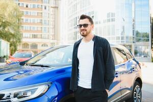 Beau Jeune homme dans permanent près voiture en plein air photo