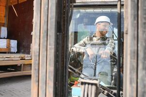 homme ouvrier à chariot élévateur chauffeur content travail dans industrie usine la logistique navire photo