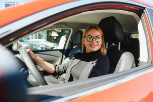 Femme d'affaires réussie au volant de voiture à travers une ville urbaine moderne avec des reflets de bâtiments photo