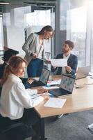 de beaux hommes d'affaires utilisent des gadgets, parlent et sourient pendant la conférence au bureau photo