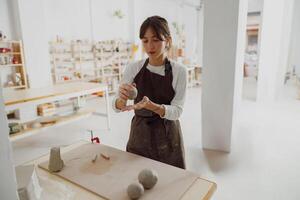 concentré céramiste femme portant tablier est en train de préparer argile à faire poterie pièces dans sa studio photo