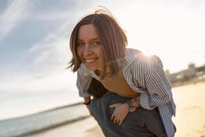 proche en haut de souriant couple dans l'amour imbécile autour tandis que en marchant le long de le plage sur ensoleillé venteux journée photo