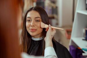 proche en haut de visage de Jeune femme avoir poudre sur sa joue avec une brosse photo