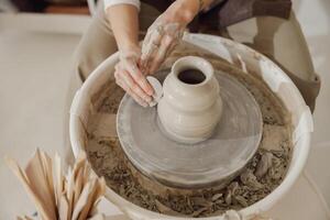 femelle potier dans tablier fabrication forme de argile vase sur filage poterie outil dans céramique atelier photo