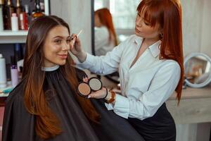 professionnel maquillage artiste Faire maquillage avec une brosse dans beauté salon photo