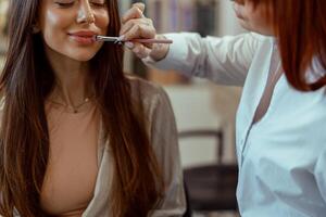 maquillage artiste s'applique rouge à lèvres à le clients lèvres dans beauté salon photo