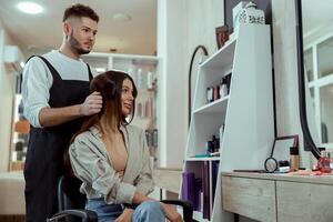 magnifique femme avec longue cheveux à la recherche heureux tandis que coiffeur Faire sa cheveux à beauté salon photo