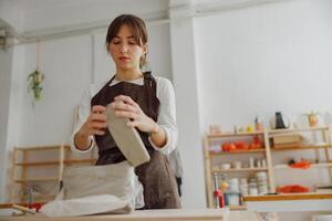 concentré céramiste femme portant tablier est en train de préparer argile à faire poterie pièces dans sa studio photo