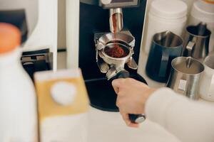 proche en haut de femelle barista broyage café en utilisant professionnel broyeur machine dans café maison photo