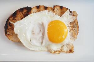 frit Oeuf sur une pain grillé sur une assiette sur une blanc Contexte photo