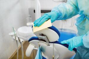 une infirmière désinfecte travail surfaces dans le dentiste bureau. photo