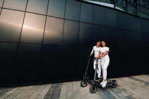 une fille et une gars sont en marchant sur électrique scooters autour le ville, une couple dans l'amour sur scooters. photo