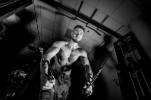 fort Jeune homme avec magnifique athlétique corps Faire des exercices dans salle de sport. aptitude, la musculation. santé se soucier. photo