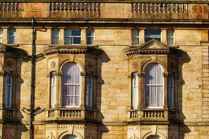 fermer de une classique grès bâtiment façade avec fleuri les fenêtres et architectural détails dans chaud lumière du soleil dans harroquer, Angleterre. photo