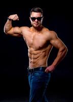 fort brutal bodybuilder homme avec parfait abdos, épaules, biceps, triceps et poitrine montrant le sien biceps. bleu filtre sur foncé Contexte photo
