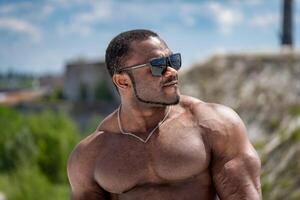 portrait de Jeune gars athlétique corps. Beau musclé dans des lunettes de soleil. photo