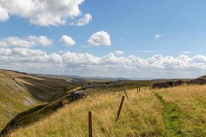 scénique campagne paysage avec roulant collines, une clair ciel, et une sentier bordé par une clôture à Malham crique, Yorkshire, Royaume-Uni. photo