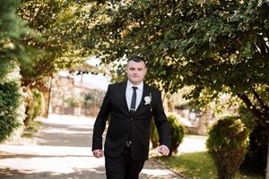 portrait de une Beau Jeune jeune marié sur un l'automne journée en plein air dans un élégant costume. Extérieur photo. Beau homme dans une affaires costume. photo