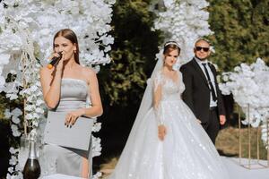 une femelle mariage présentateur donnant une discours et le la mariée et jeune marié photo