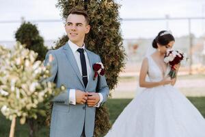 le moment de le premier réunion de le la mariée et jeune marié avec une mariage bouquet, le la mariée va à sa amoureux dans la nature en dessous de le l'automne Soleil. photo