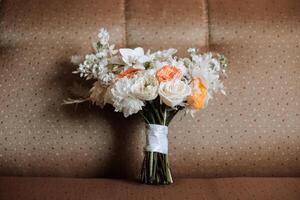 mariage bouquet. fraîchement Couper des roses, vert la graine têtes et feuilles. vert tiges, blanc ruban et or mariage anneaux. le concept de une mariage bouquet. photo