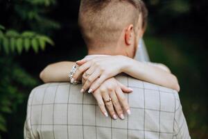 les mariées main bras autour jeune marié. mariage journée moment. la mariée en portant mariés épaule, dans l'amour couple sur mariage journée ensemble. la mariée et jeune marié. fleurs et anneaux. les mariées main en portant jeune marié. photo