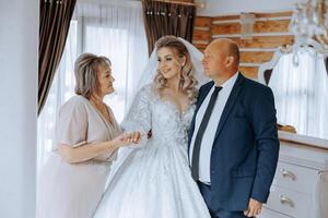 content Parents tenir le mains de le la mariée qui est avoir marié et soutien son, portant une mariage robe et une longue voile. photo