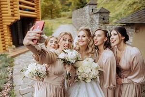 mariage la photographie. une blond la mariée dans une blanc robe détient une bouquet et prend une selfie photo