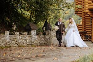 une mariage couple est en marchant dans la nature sur un l'automne journée. content Jeune la mariée et élégant jeune marié en portant mains. une élégant couple de jeunes mariés sur leur mariage journée. photo