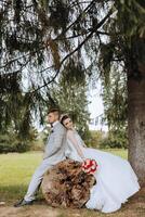 charmant jeunes mariés dans une magnifique emplacement. le la mariée dans une blanc mariage robe suivant à sa amoureux, le jeune marié des stands proche et détient le les filles main. photo