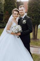 élégant, Jeune jeune marié et magnifique la mariée dans une longue blanc robe et une longue voile avec une bouquet dans leur mains, étreindre dans le parc dans le l'automne la nature. mariage portrait de jeunes mariés. photo