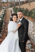 élégant, Jeune jeune marié et magnifique la mariée dans une longue blanc robe et une longue voile avec une bouquet dans leur mains, étreindre dans le parc dans le l'automne la nature. mariage portrait de jeunes mariés. photo