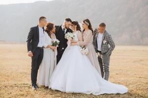 mariage photo session dans la nature. le la mariée et jeune marié baiser et leur copains