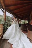le la mariée dans une blanc robe avec une longue train sur une en bois belvédère photo