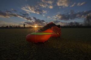 des sports des chaussures sur le Contexte de le champ à le coucher du soleil. Football champ avec baskets photo