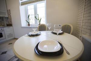 table avec assiettes et des lunettes sur le Contexte de une petit cuisine photo