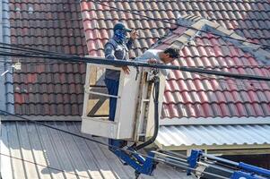 le Publique travaux département est organiser désordonné télécommunications et électrique câbles en utilisant une ciel ascenseur voiture, Indonésie, 19 décembre 2023. photo