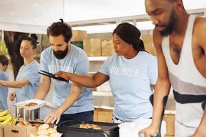 Jeune bénévoles cuisinier et main en dehors nourriture à le nécessiteux. désactivée personnes et Multi-éthnique gens viens ensemble à fournir abri et humanitaire aide promouvoir unité et la compassion dans communauté. photo